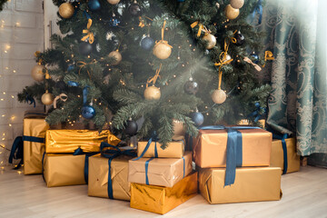 Photo of luxury gift boxes under Christmas tree, New Year home decorations, golden wrapping of Santa presents, festive tree decorated with garland, baubles, traditional celebration. 