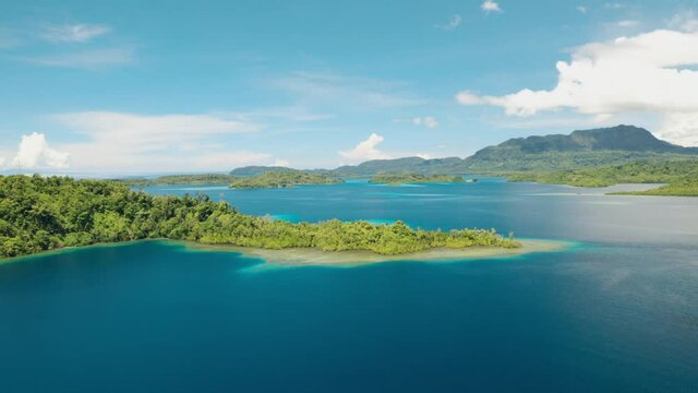 Aerial view and pan of a tropical island in a big harbour during midday.