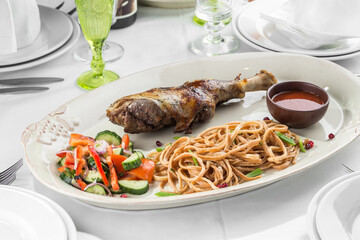 Braised lamb shank with fresh vegetable salad and noodles on the table