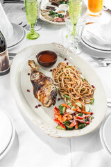 Braised lamb shank with fresh vegetable salad and noodles on the table