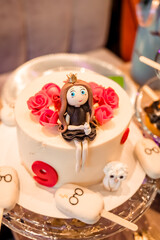 the cake is white with a girl sitting on it in a black dress. Birthday celebration for 9 years.