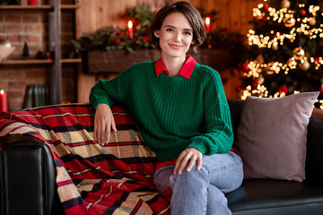Photo of shiny charming young lady wear green pullover smiling having rest sitting couch indoors house home room