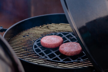 Process of grilling fresh meat cutlets for burgers on brazier at summer local food market - close up view. Outdoor cooking, gastronomy, cookery and street food concept