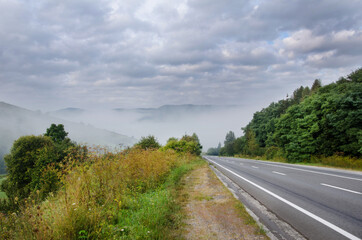 Fototapeta na wymiar dramatic landscape. morning in the mountains. fog in the background. landscape of early autumn. road to the mountains