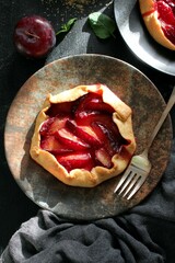 Tasty cake with plums on dark background. Top view with copy space. Healthy food.