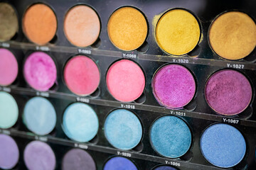 Colorful eyeshadow pallet for make up in cosmetic store - close up view. Makeup, beauty, fashion and glamour concept