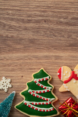 Decorated Christmas gingerbread cookies with decorations on wooden table background.