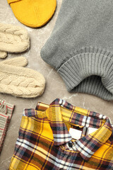 Concept of winter clothes on gray textured table