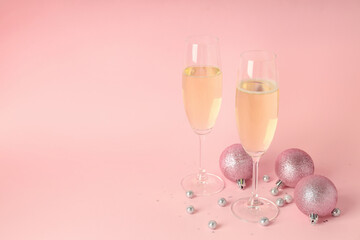 Glasses of champagne and baubles on pink background
