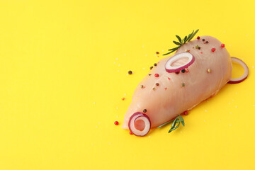 Raw chicken fillet with spices on yellow background