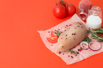 Raw chicken fillet with ingredients on orange background