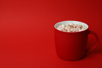 Cocoa with marshmallows in cup on red background