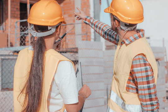 Joven equipo de constructores de arquitectura e ingenier&iacute;a realizando trabajos de obra y se&ntilde;alando la estructura del edificio para realizar las maquetas y objetivos de construcci&oacute;n