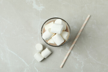 Cocoa with marshmallows in glass on light background