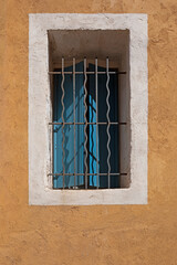 Fenêtre de rez-de-chaussée avec barreaux d'une maison dans la ruelle d'une vieille ville du Sud de la France à la façade colorée. Ville de Sète.