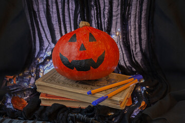 Halloween pumpkin on books with pens. Concept for Halloween celebration in school or college....