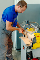 An adult turner in glasses and working overalls works at the machine. Authentic scene. Real workflow in the turning shop.