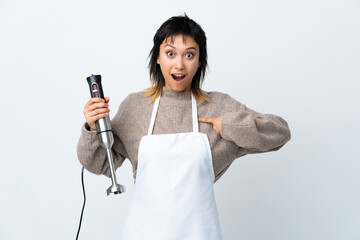 Chef Uruguayan girl using hand blender over isolated white background with surprise facial expression