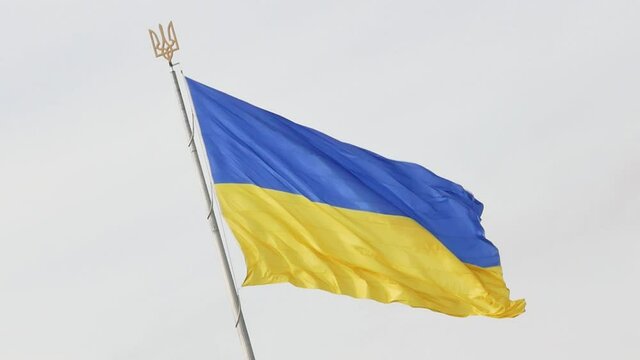 Large Ukrainian flag waving in the wind. National Blue yellow flag of Ukraine against blue sky