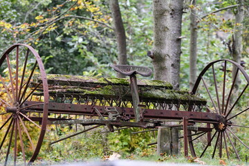 Decaying old farm machine plow along the edge of an  over grown meadow