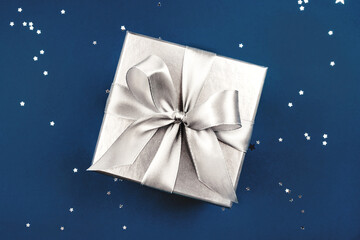 Silver gift box with bow on blue background.