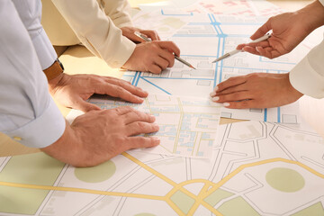 Professional cartographers working with cadastral map at table, closeup