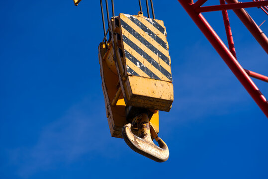 Close-up of arm of mobile crane with yellow and black painted hook with blue sky background. Photo taken September 30th, 2021, Zurich, Switzerland.