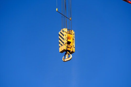Close-up of arm of mobile crane with yellow and black painted hook with blue sky background. Photo taken September 30th, 2021, Zurich, Switzerland.