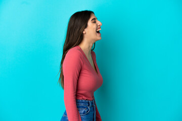 Young caucasian woman isolated on blue background laughing in lateral position