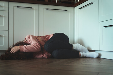 Young woman with covered face lying on floor in the kitchen