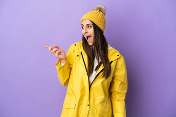 Young caucasian woman wearing a rainproof coat isolated on purple background intending to realizes the solution while lifting a finger up