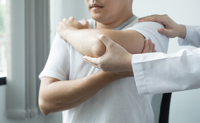 Obraz premium Female physiotherapists provide assistance to male patients with elbow injuries examine patients in rehabilitation centers. Physiotherapy concepts