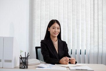 Asian businesswomen sit at their desks and calculate financial graphs showing results about their...