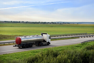 Isothermal Tank truck driving on highway. Oil and Gas Transportation and Logistics. Metal chrome...