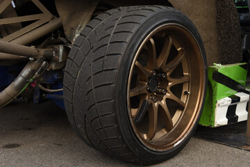 Tires of race car for driving. Drag and drift car with lower-profile tire. Racing low profile tyre with brake disc. Alloy wheel with calipers and racing brakes of the sport cars. Tyres background.