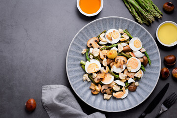 Salad with chestnuts, mushroom, asparagus and eggs on grey stone background, top view, autumn dish, flat lay, copy space