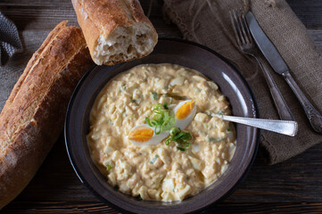 Egg salad with fresh baguette on wooden table