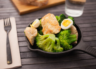 healthy appetizer of chicken pieces with broccoli and quail eggs in small cast iron skillet