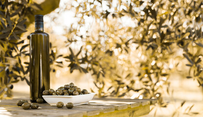 green olives and oil on table in olive grove