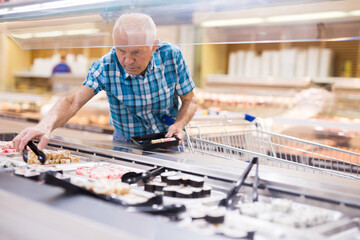 elderly retired senor buying sushi in buffet department of supermarket