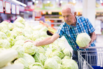 old age man choosing cabbage in supermarket