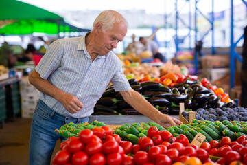 retired european man buying tomatoes in market