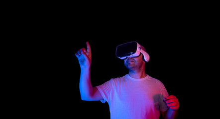 Young man using vr glasses in black background and neon light environment.