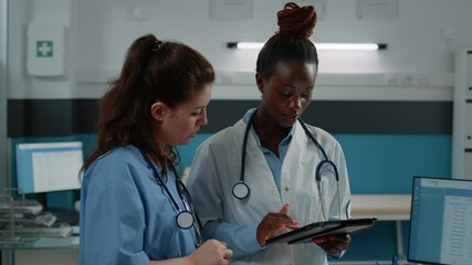 Group of medical workers using tablet for consultation and patient healthcare in doctors office. Team of doctor and nurse with stethoscope working with touch screen device for practice. - Powered by Adobe