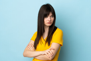 Teenager Ukrainian girl isolated on blue background keeping the arms crossed