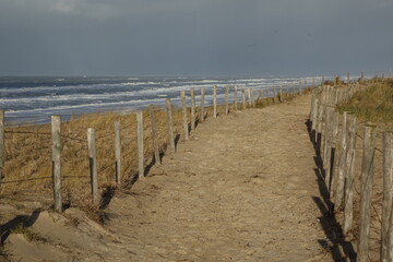 Clôturé dans un chemin de dunes de sable sur une plage de la mer du Nord avec des vagues sur un matin d& 39 hiver ensoleillé et orageux, Egmond aan Zee, Hollande du Nord, Pays-Bas