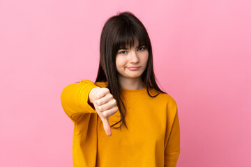 Young Ukrainian woman isolated on pink background showing thumb down with negative expression
