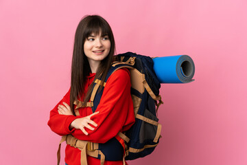 Mountaineer Ukrainian girl with a big backpack isolated on pink background looking to the side
