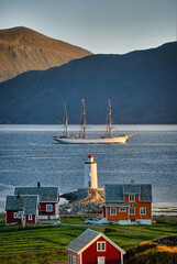 Tall ship Statsraad Lehmkuhl passing Høgstein lighthouse before sailing towards the open sea, Godøy, Norway