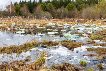 forest area in spring, water and yellow grass in which there are a lot of plastic bags and other...